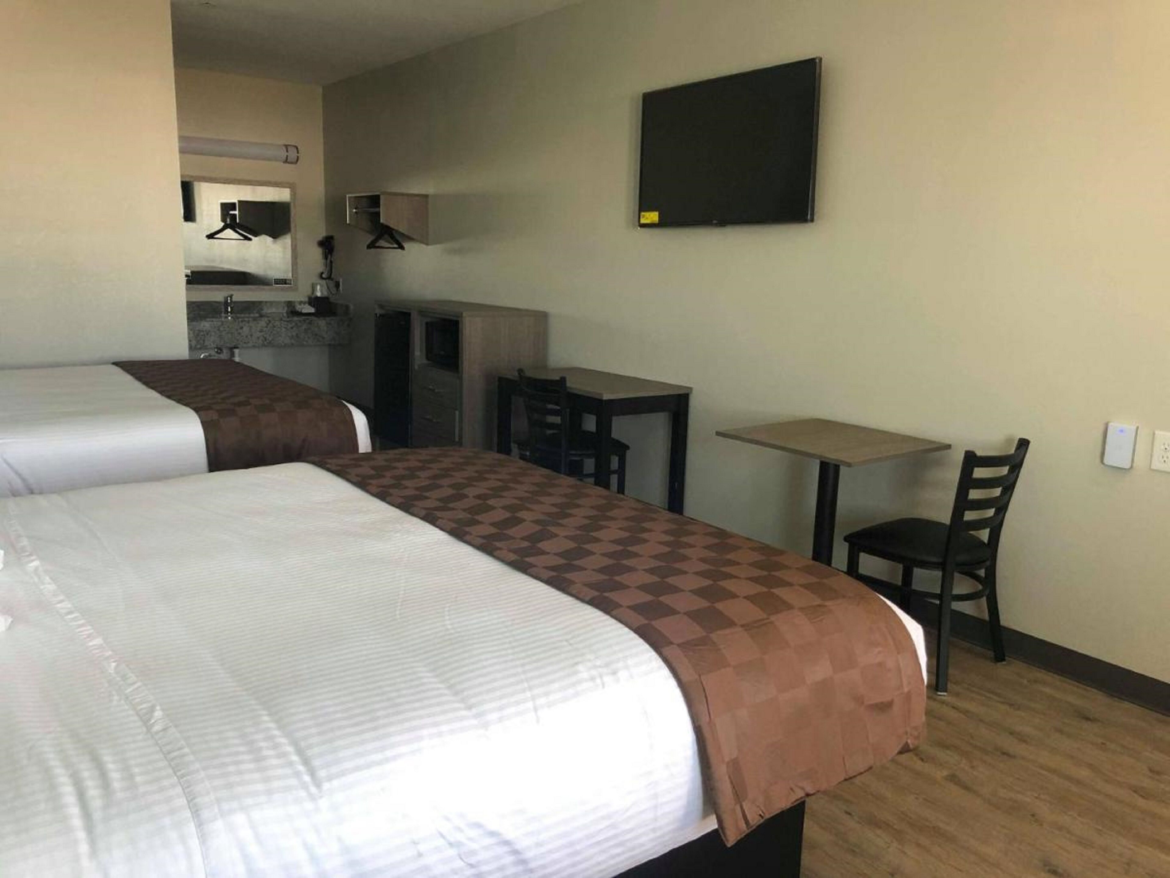 Une chambre d’hôtel avec deux lits, un bureau, une chaise et une petite table.