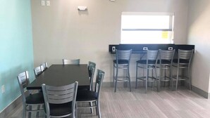 Una sala de conferències amb una taula gran i cadires, una finestra amb persianes i un escriptori petit amb un ordinador.
