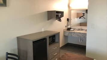 Una habitación compacta con kitchenette, un escritorio pequeño y una silla.