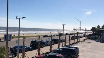 A parking lot with cars and a beach in the background.