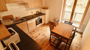 Una cuina moderna amb armaris de fusta, rentaplats, forn i zona de menjador amb taula i cadires.