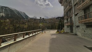 Un edifici modern amb façana de pedra i balcons, amb vista a un paisatge muntanyós.