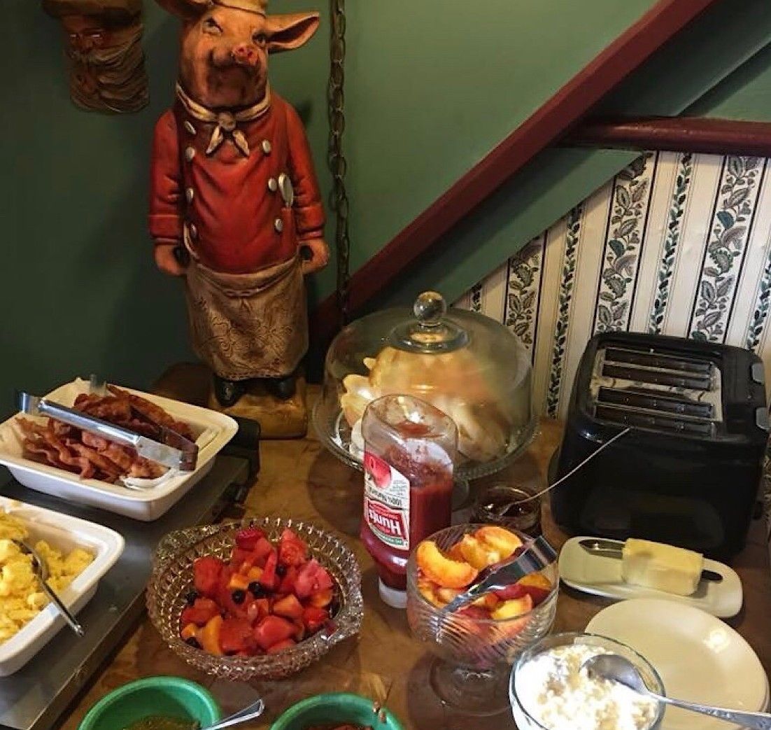 A breakfast buffet with various food items, a toaster, and a decorative pig statue.