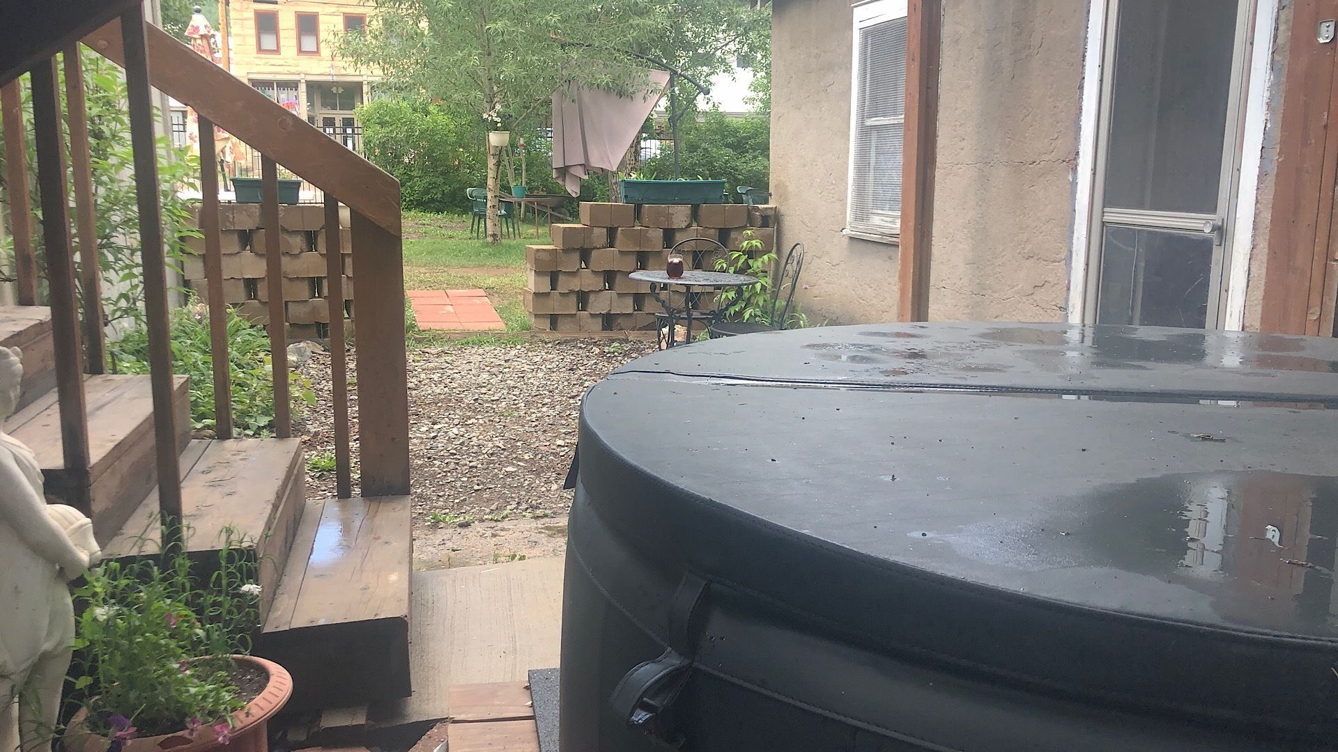 A patio area with a hot tub, a brick wall, and a small table with chairs.