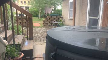 A patio area with a hot tub, a brick wall, and a small table with chairs.