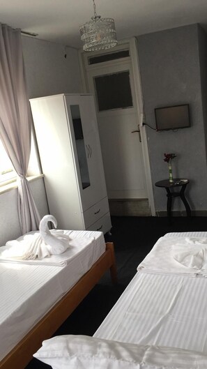 A hotel room with two beds, a wardrobe, a small table with a vase, and a television on the wall. - View hotel (Marmaris)