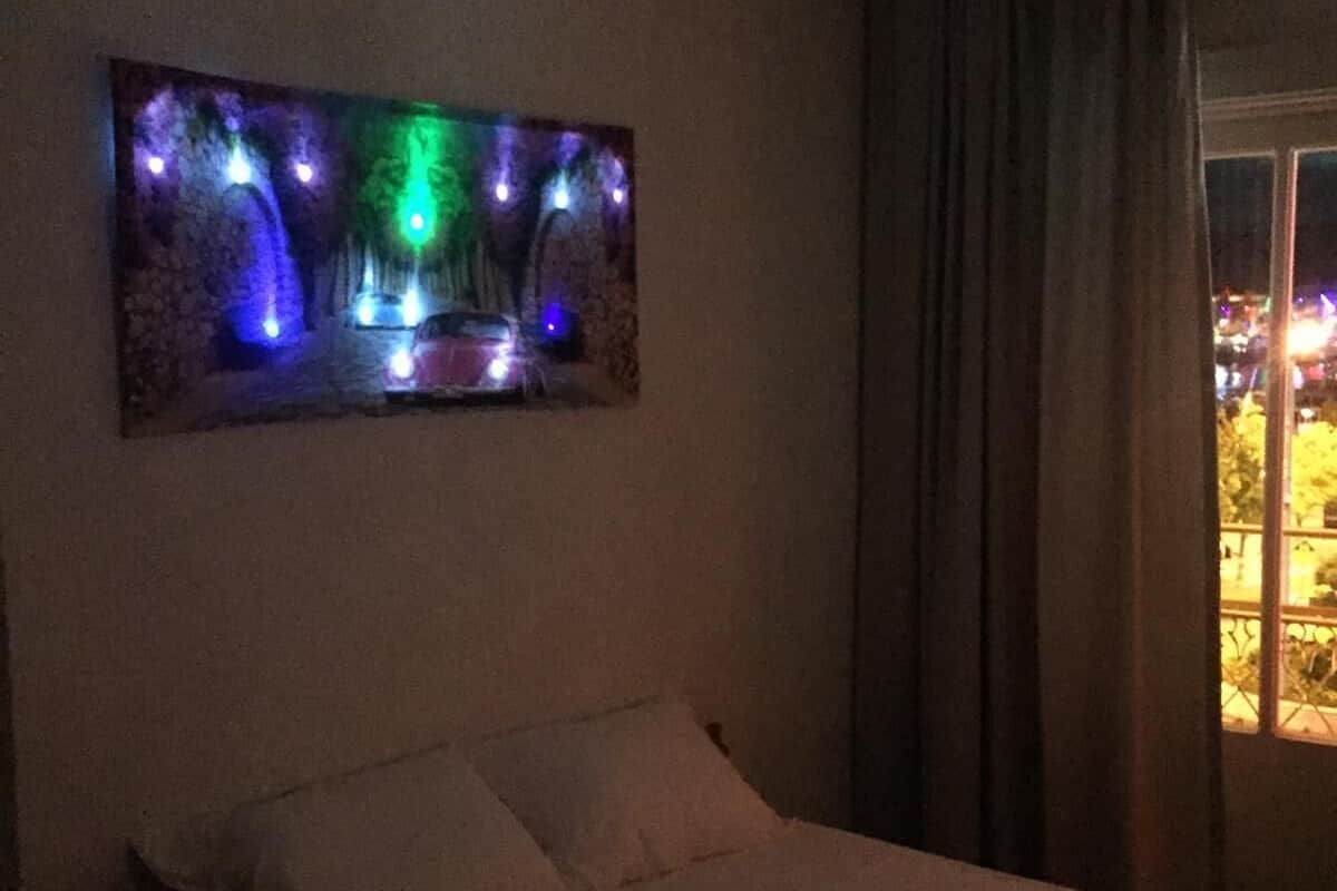 A bedroom with a bed, a wall-mounted artwork, and a window with curtains.