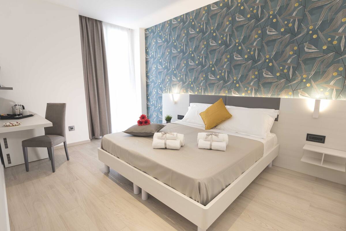 Une chambre d’hôtel moderne dotée d’un grand lit, d’un bureau et offrant une vue sur l’extérieur.