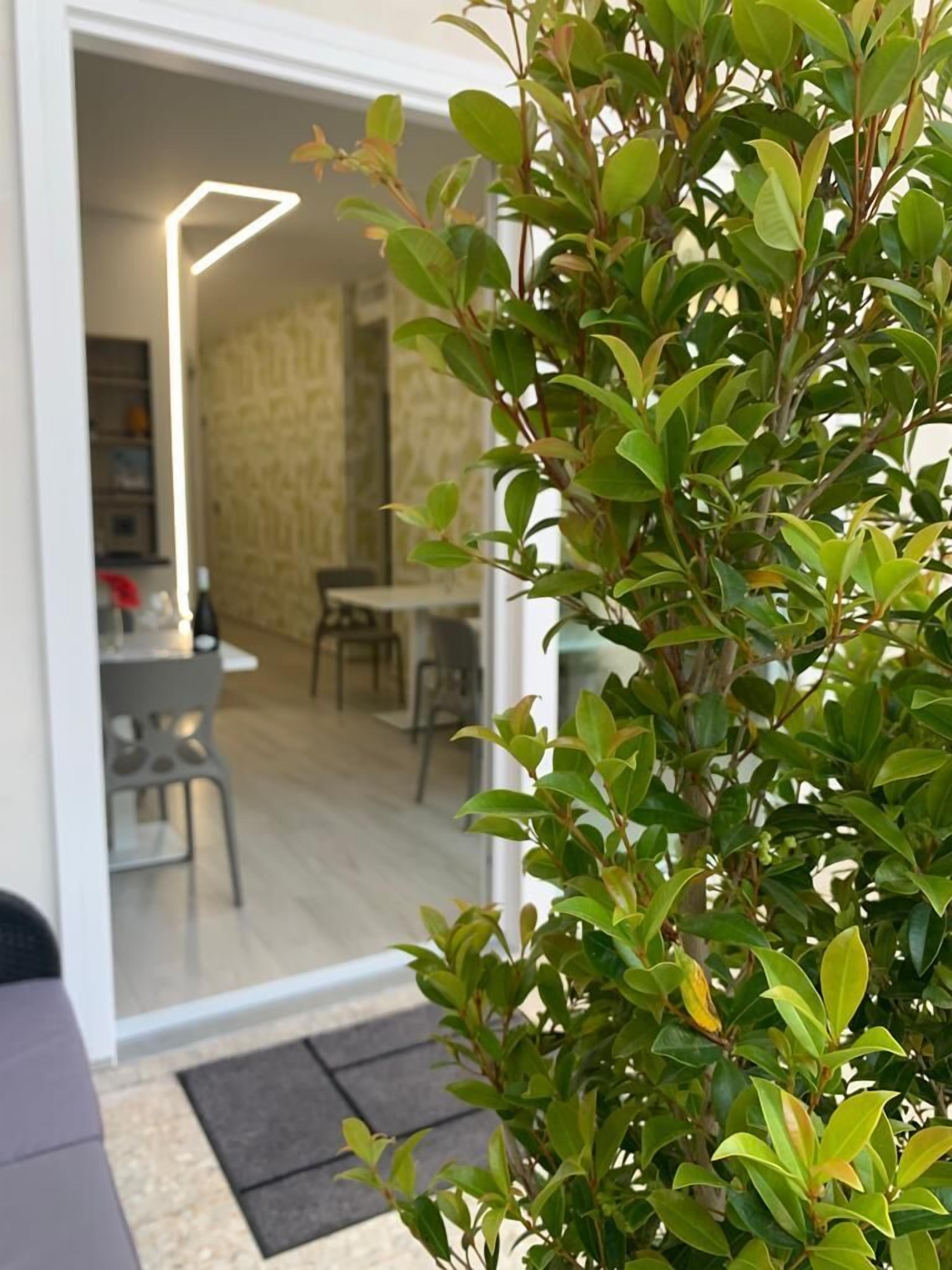 A modern interior with a dining area, a staircase, and a potted plant.