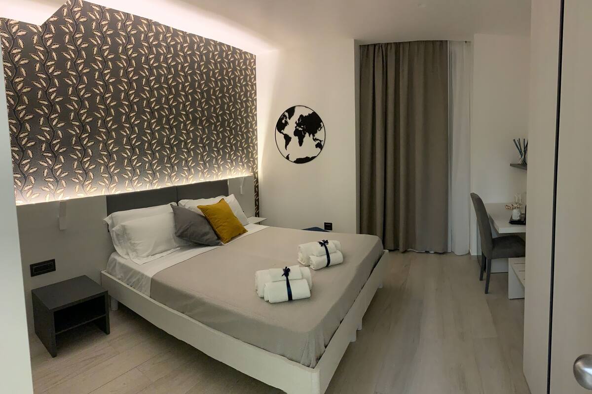 Une chambre d’hôtel bien rangée, avec un lit, une table de chevet et un bureau.