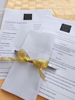 A hotel room brochure with a gold ribbon tied around it, placed on a textured fabric background.
