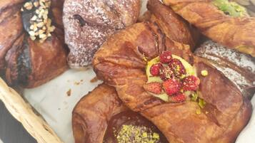 A basket of assorted pastries, including croissants and pastries with toppings like nuts and fruit.