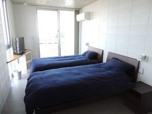 Une chambre d’hôtel avec deux lits, un téléviseur posé sur une étagère et une fenêtre donnant sur des immeubles.