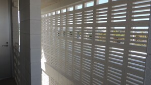 A corridor with a white partition featuring horizontal slats.
