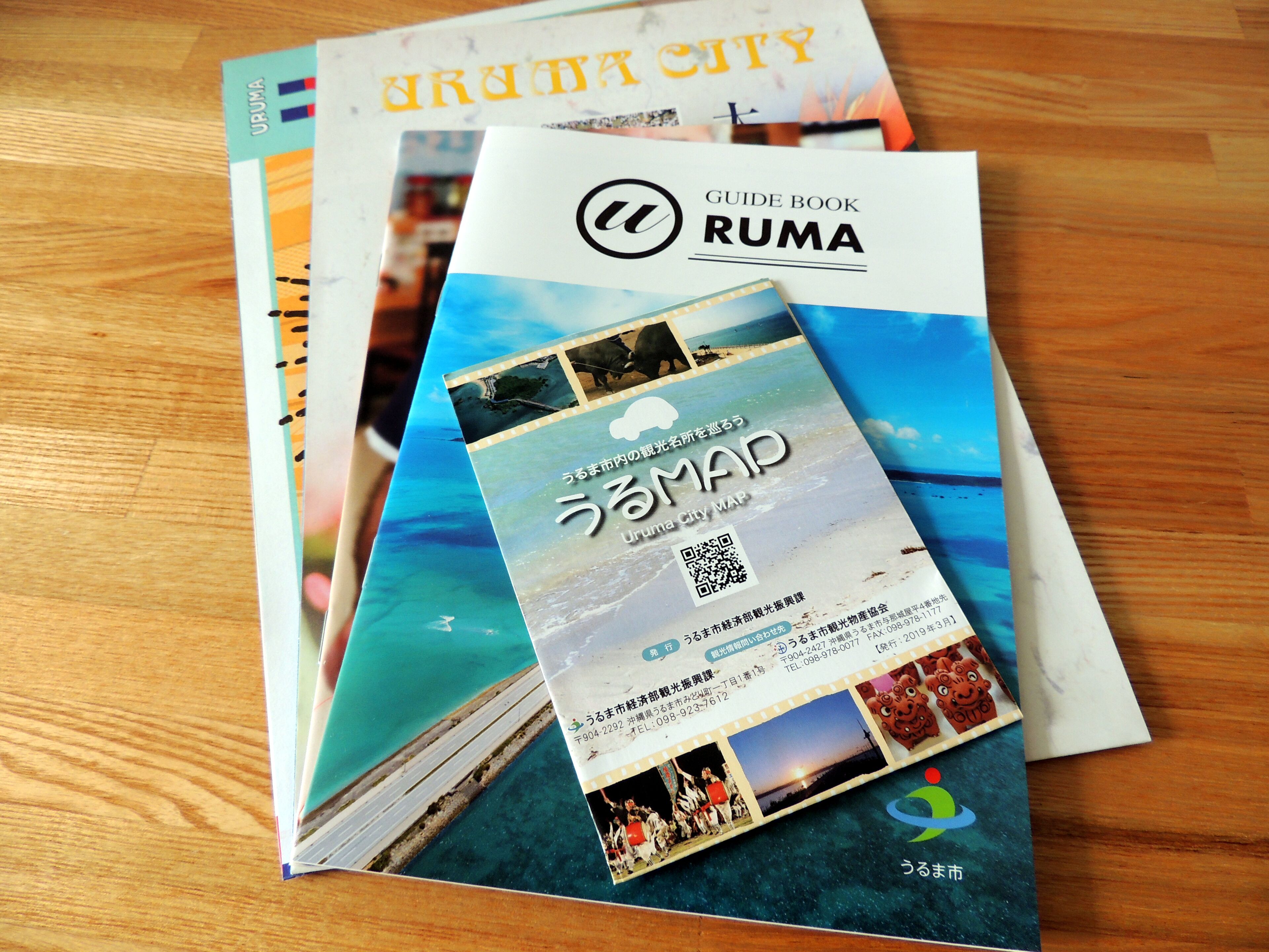 A stack of guide books for Ruma City, including a map and various photographs of the city.