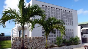 A modern building with a stone wall and palm trees in front.