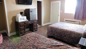 A hotel room with two beds, a TV, a microwave, a refrigerator, and a dresser. - American Star Inn (Munday)