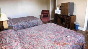 A hotel room with two beds, a TV, a microwave, a dresser, and a chair.