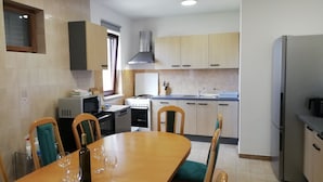 Una cocina moderna con comedor. Incluye estufa, horno, lavaplatos y refrigerador.