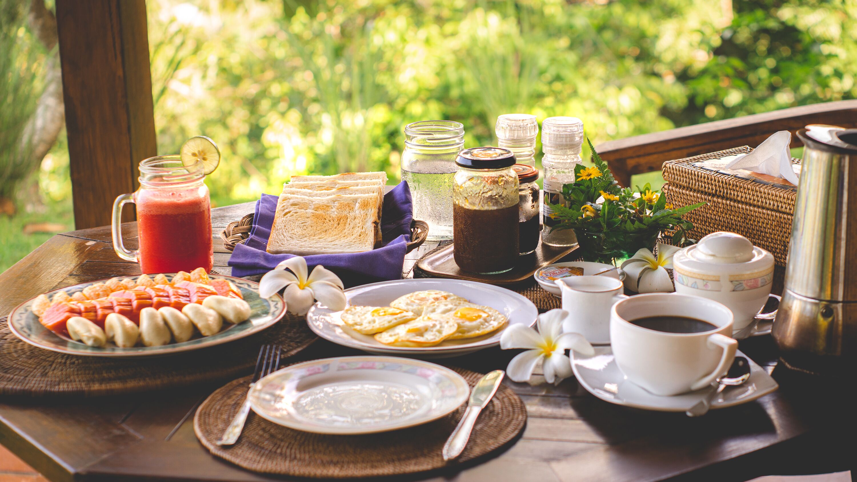 A breakfast table with various food items, a coffee pot, and a mug.