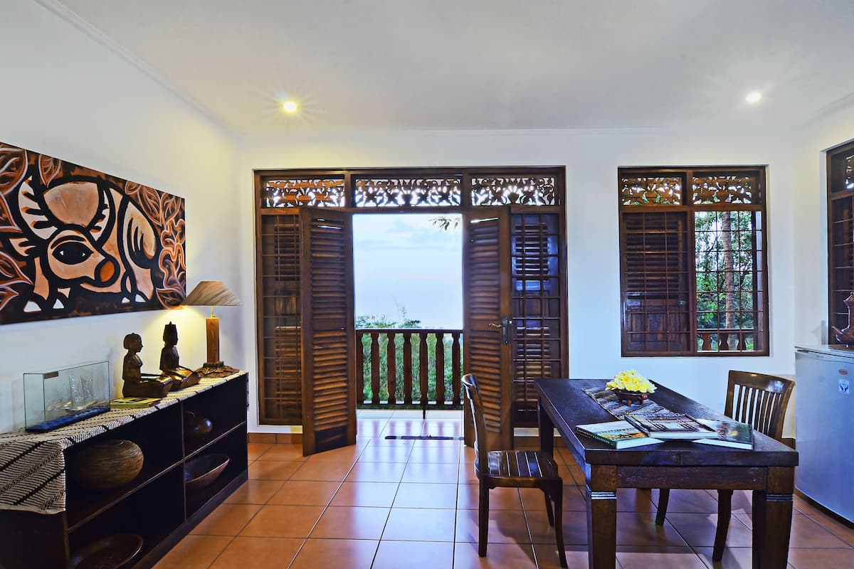 A dining area with a table, chairs, and a view through a wooden door.