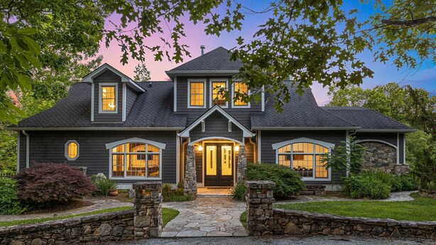 A two-story house with a stone facade, a stone entrance, and a well-maintained lawn. - Waterfall Manor | Mountain Luxury w/ Fireplaces & Views + Biltmore Pass (Fletcher)