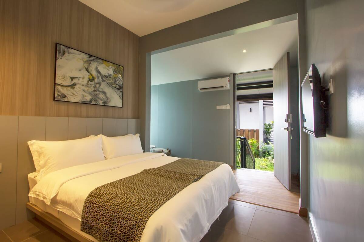 A modern hotel room with a large bed, a painting on the wall, and an air conditioning unit.