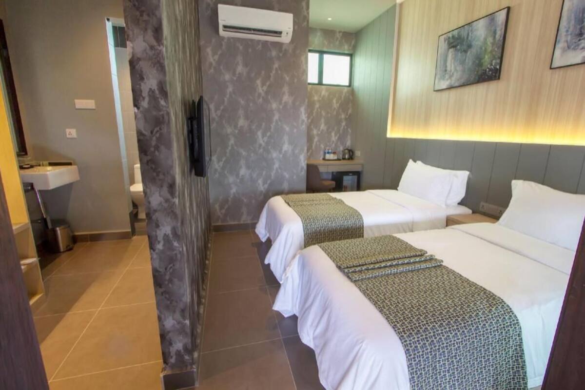 A hotel room with two beds, a bathroom, a sink, and a small kitchenette.