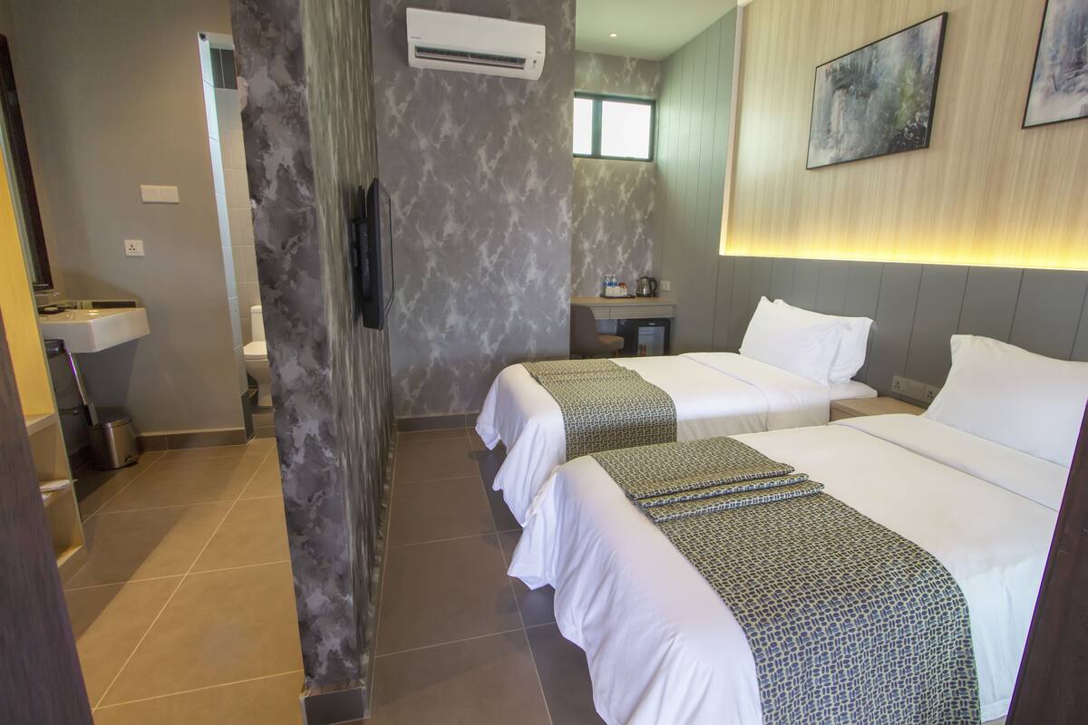 A hotel room with two beds, a bathroom, a sink, and a small kitchenette.