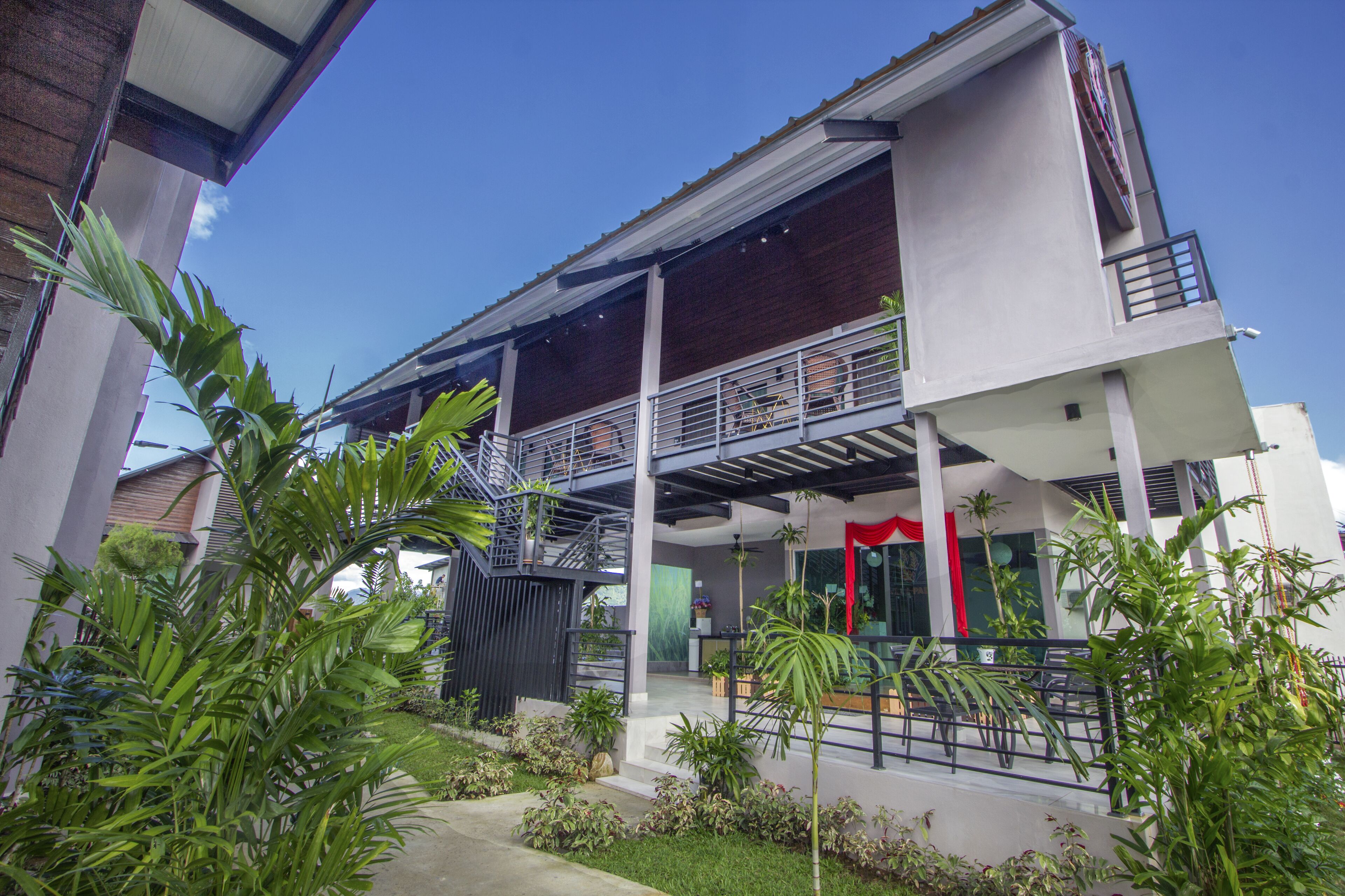 A modern two-story building with a covered outdoor area, a balcony, and a red decorative element.