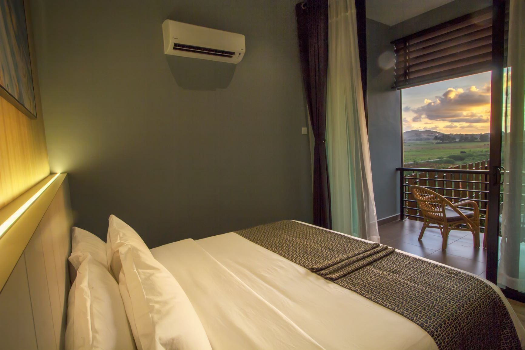 Ein Hotelzimmer mit Bett, Klimaanlage, einem Balkon mit Stuhl und Blick auf die Landschaft.