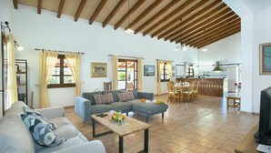 A spacious living room with a sofa, a dining area with a table and chairs, and a kitchen in the background. - VILLA ROMEU - 10 MIN WALK TO THE OLD TOWN (Pollensa)