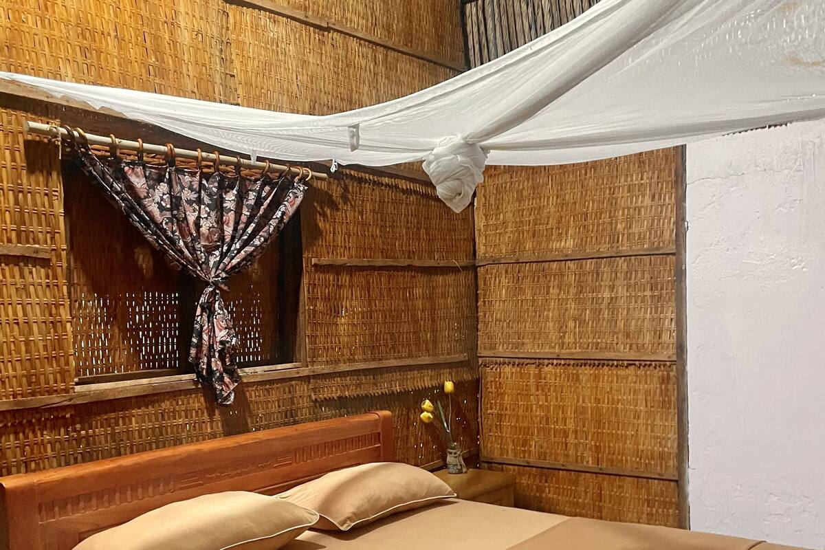 Una habitación con una cama, dosel y pared de tejido.