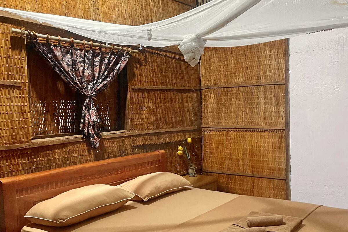 Una cama con dosel, cabecero de madera y mesita de noche con lámpara.