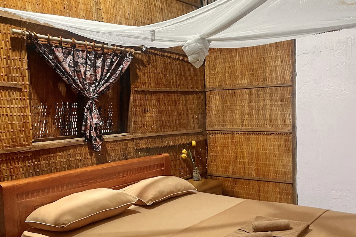 Ein Zimmer mit einem Bett, einem Baldachin und einer gewobenen Wand.