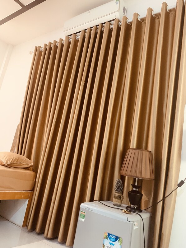 A room with a bed, a water dispenser, and a lamp on a table. - Phuc Sinh Homestay (Chau Thanh)