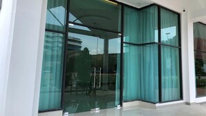 Un edificio moderno con grandes puertas y ventanas de vidrio, fachada blanca y pulcra, y suelo de baldosas.