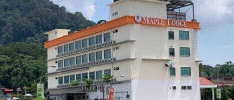 Un hotel de varios pisos llamado Maple Lodge con techo plano y un cartel.