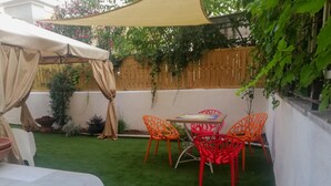 A patio area with a table and chairs, a covered seating area, and a green lawn. - AlbaChiara B&B (Gaeta)