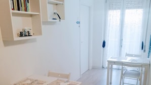 A spacious room with a wooden floor, a dining table with chairs, and bookshelves. - AlbaChiara B&B (Gaeta)