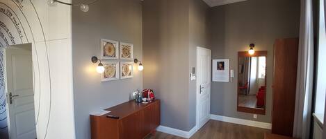 A modern living room with a wooden floor, a red sofa, a wooden cabinet, and a chandelier.