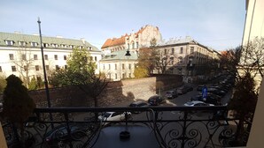 Uma varanda com vista para a paisagem urbana, incluindo edifícios históricos e um estacionamento.
