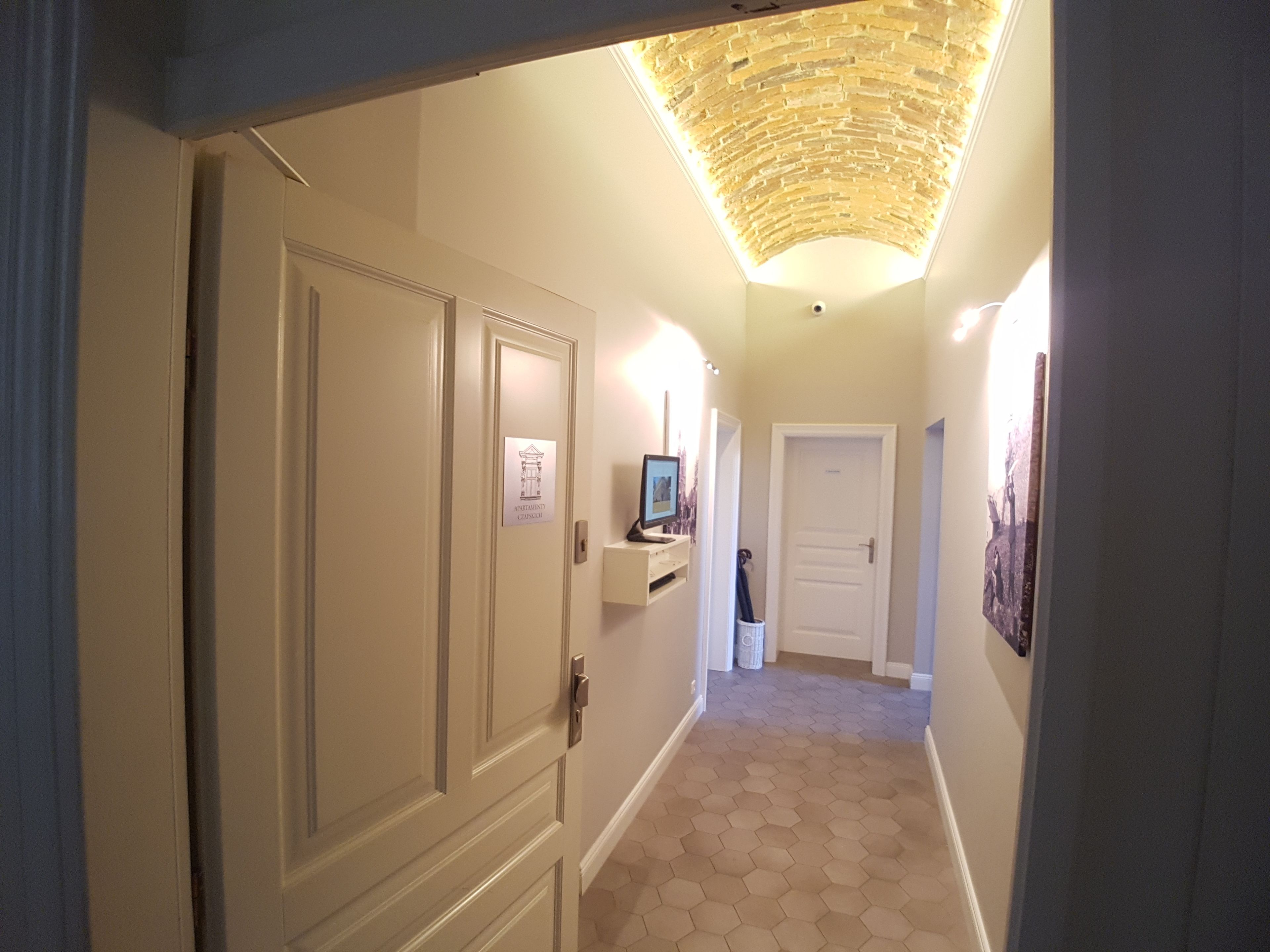 A hallway with a tiled floor, a ceiling light fixture, and a door with a sign.