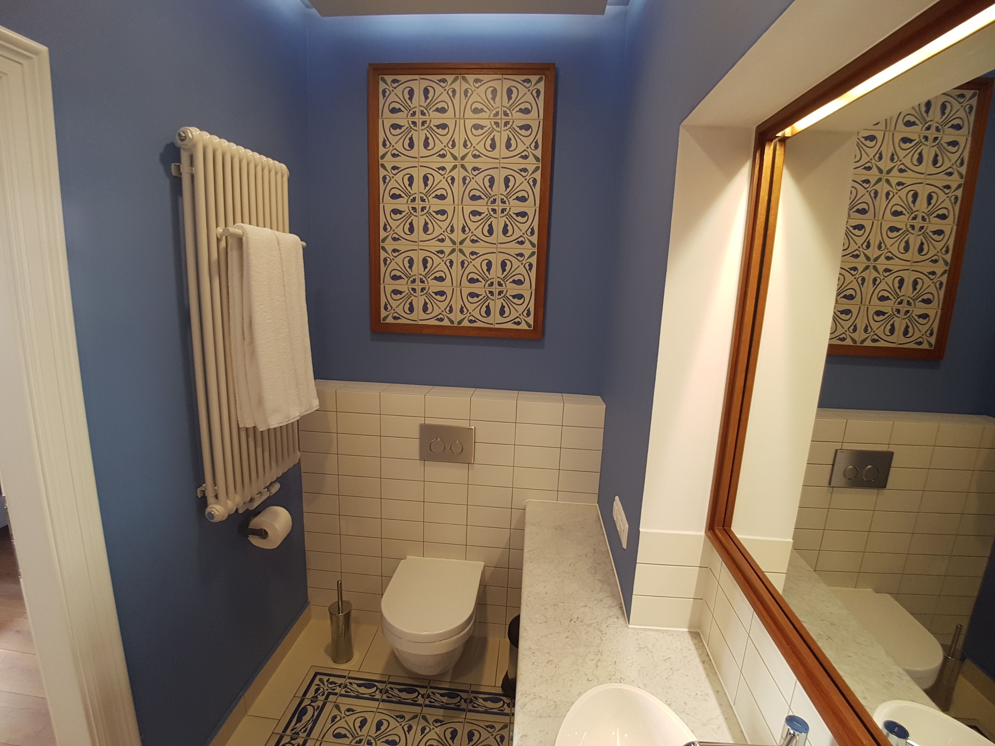 Ein Badezimmer mit Toilette, Heizkörper und Spiegel.