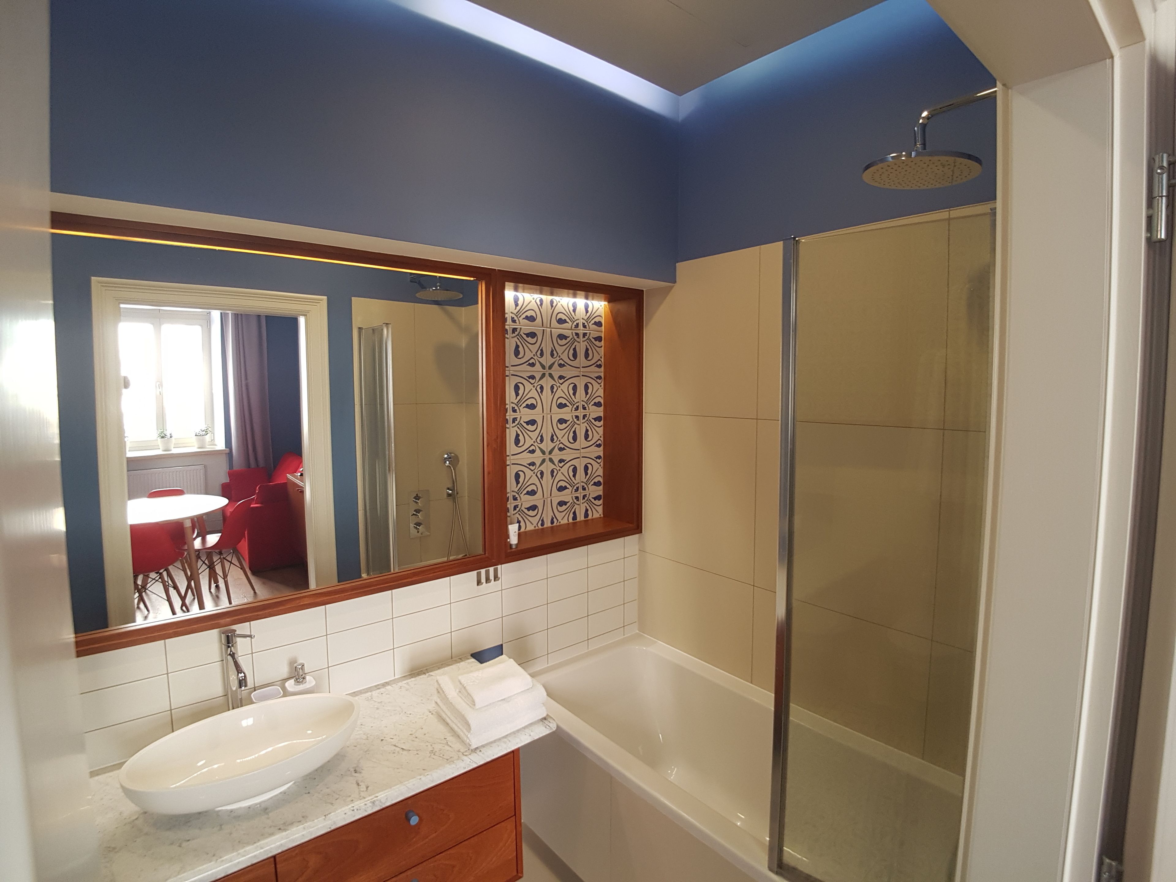 A bathroom with a large mirror, a sink, a bathtub, and a shower.