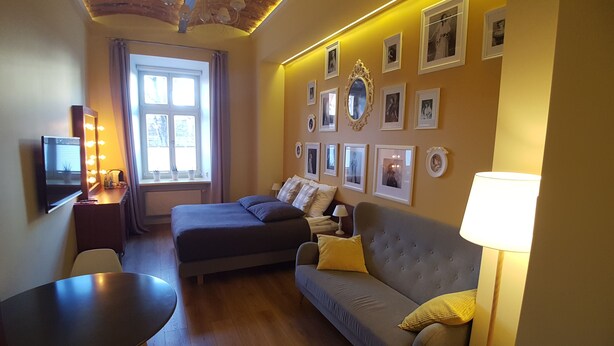 Um quarto de hotel aconchegante com uma cama, um sofá, uma escrivaninha com espelho e uma televisão.