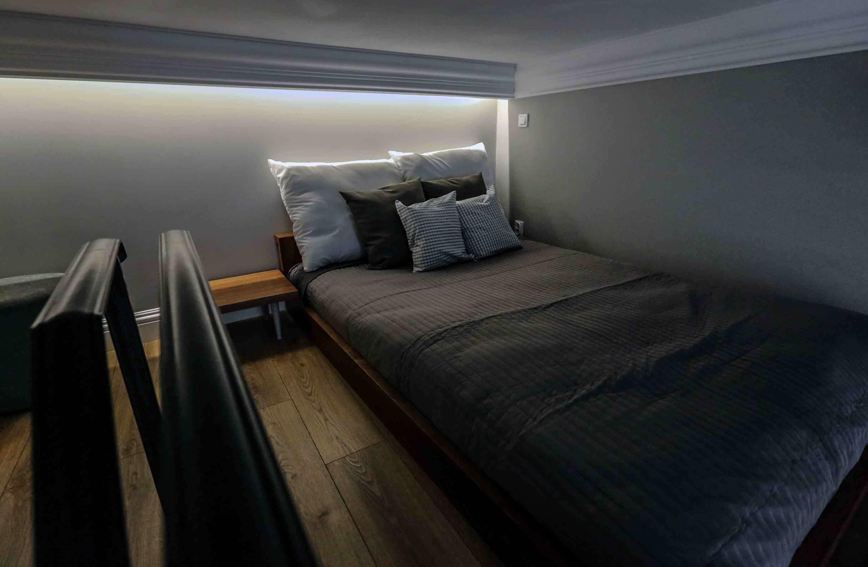 A small, neatly arranged bedroom with a bed, bedside tables, and a bench.