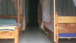 Un couloir avec deux lits en bois, chacun surmonté d’un baldaquin.