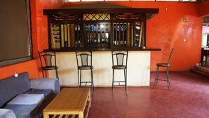 Un espace bar avec un comptoir et quatre chaises, un canapé et une table en bois.