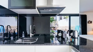Una cocina moderna con encimera negra, electrodomésticos de acero inoxidable y vistas al exterior.